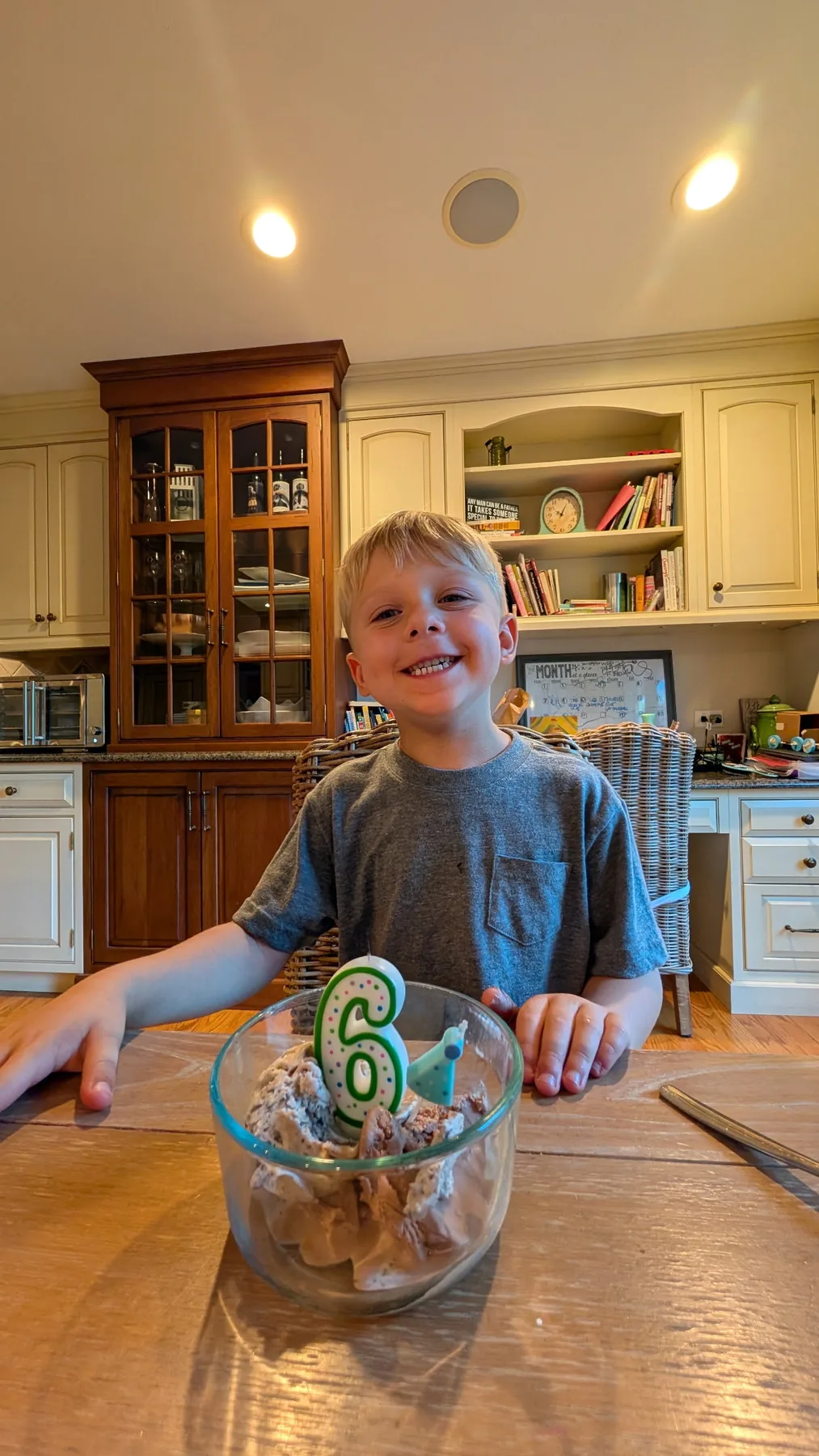 Caleb holding a candle-lit birthday treat in the kitchen