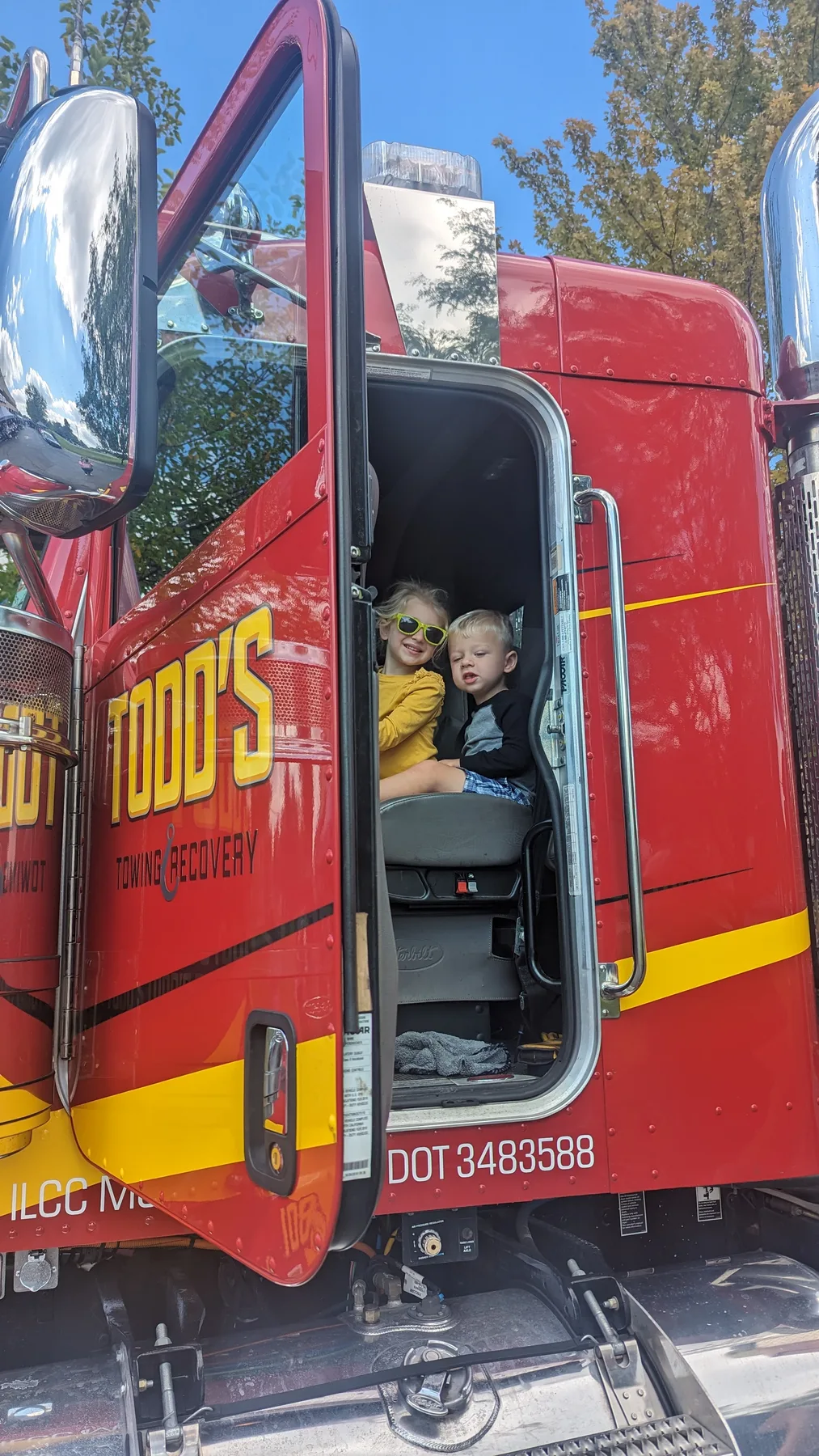 Caleb sitting up in the cab of a large red semi truck