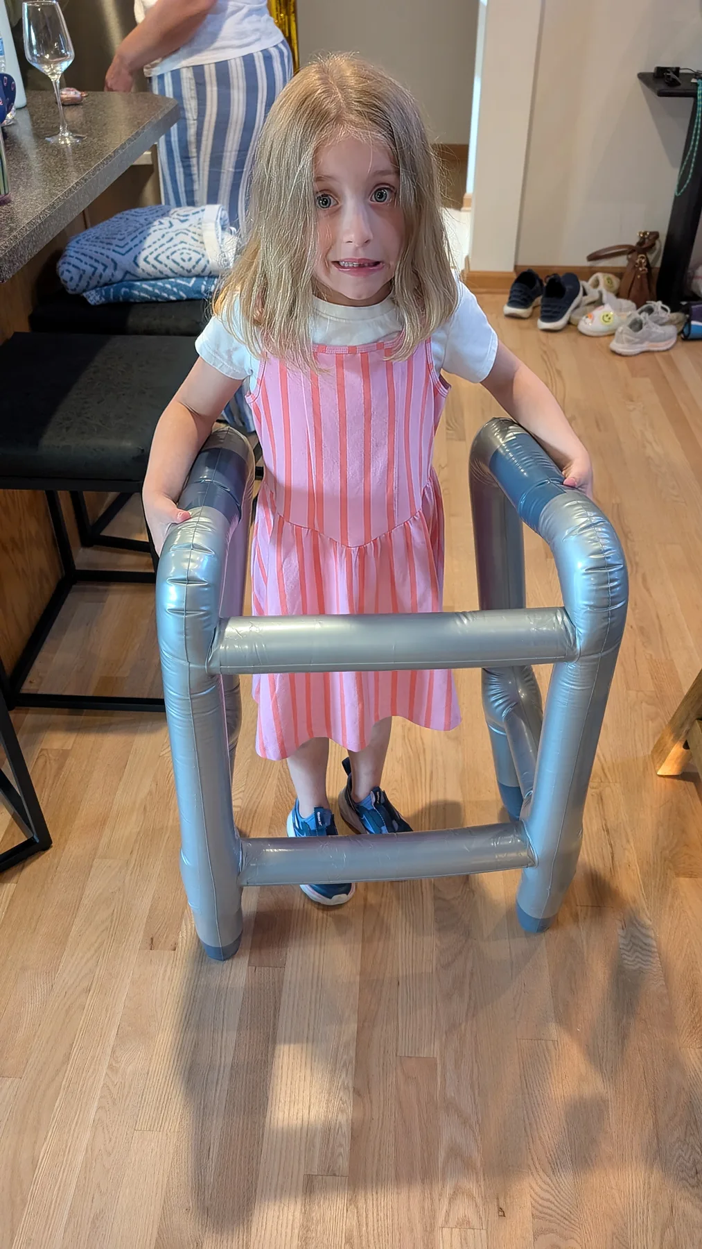 Abigail in a striped dress with an inflatable walker, playing at home