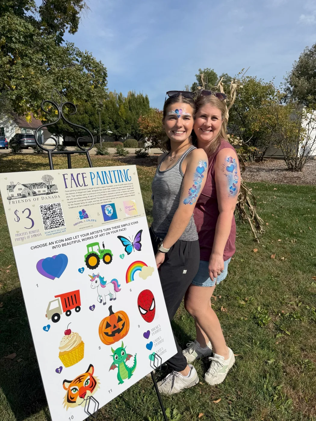 Volunteers beside the Friends of Danada face painting sign, showing the designs children could choose from